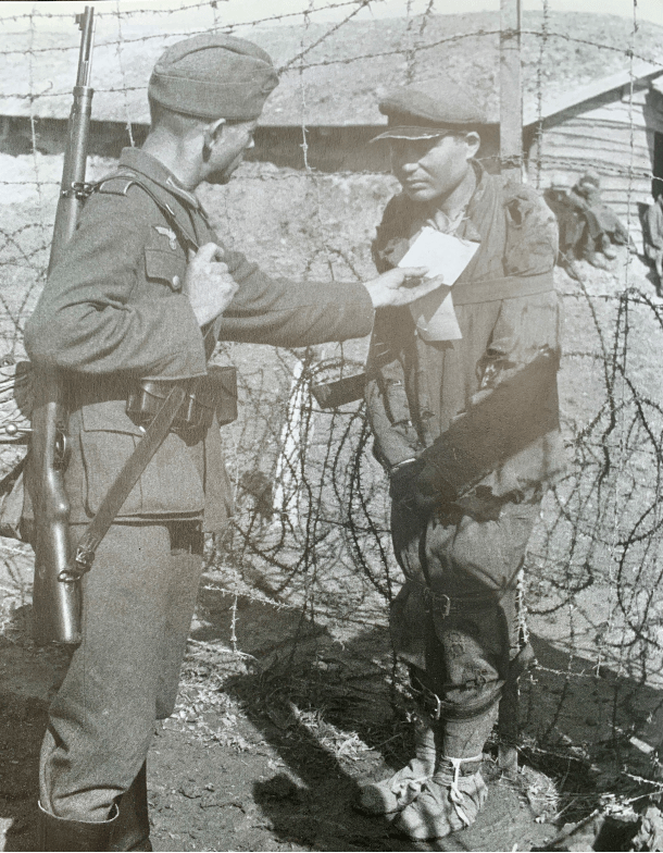 Wehrmachtssoldat mit gefesseltem sowjetischem Kriegsgefangenem in einem Lager bei Chelm in Polen, vermutlich 1941.