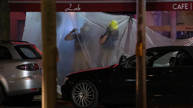 Feuerwehrleute hängen vor einem Lokal in der Müllerstraße Planen auf: In Berlin-Wedding sind am späten Sonntagabend mehrere Schüsse gefallen.