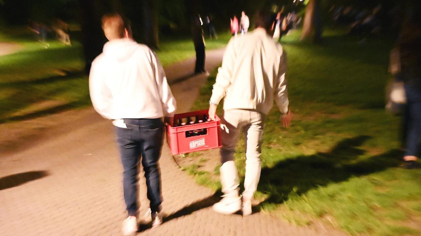 Jugendliche tragen einen Kasten Bier in einen Park (Symbolbild): Viele junge Erfurter haben das Sommerwetter zum Feiern genutzt.