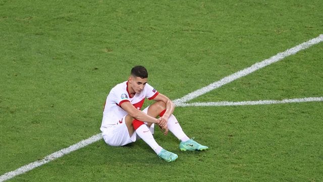 Der türkische Nationalspieler Mert Müldür sitzt nach dem EM-Aus auf dem Rasen.