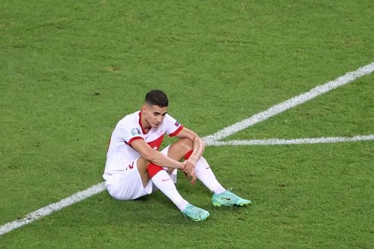 Der türkische Nationalspieler Mert Müldür sitzt nach dem EM-Aus auf dem Rasen.