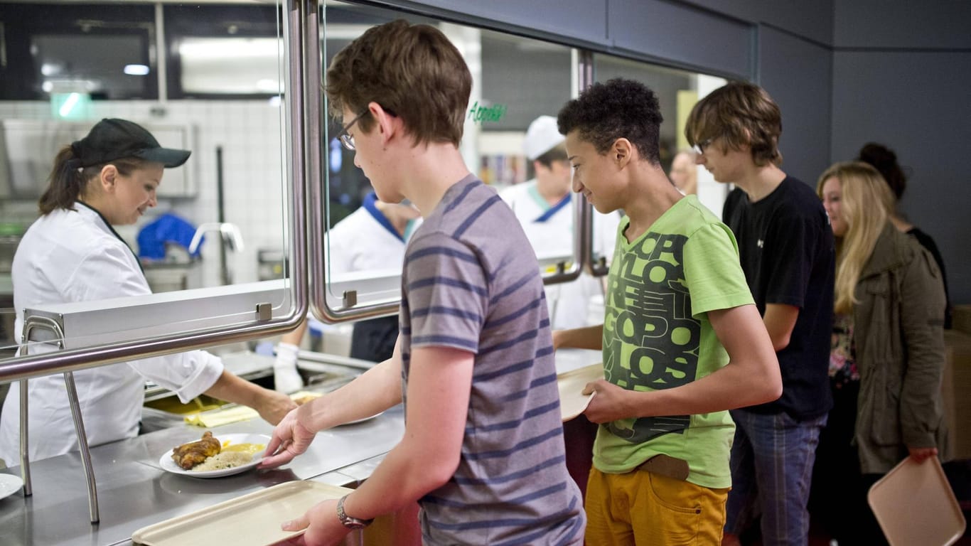 Schüler stehen in der Schulkantine an der Essensausgabe an (Symbolbild): In vielen Mensen werden subtile Arten des "Nudging" benutzt, um die Essensauswahl der Schüler zu lenken.