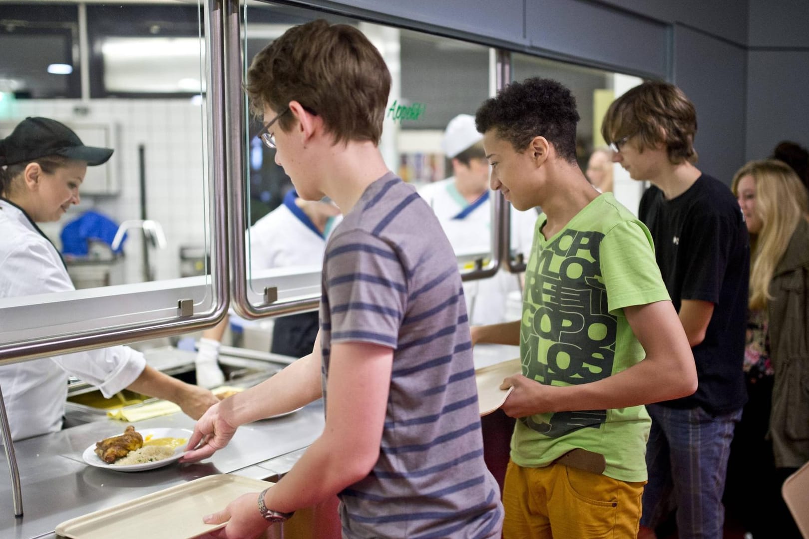 Schüler stehen in der Schulkantine an der Essensausgabe an (Symbolbild): In vielen Mensen werden subtile Arten des "Nudging" benutzt, um die Essensauswahl der Schüler zu lenken.