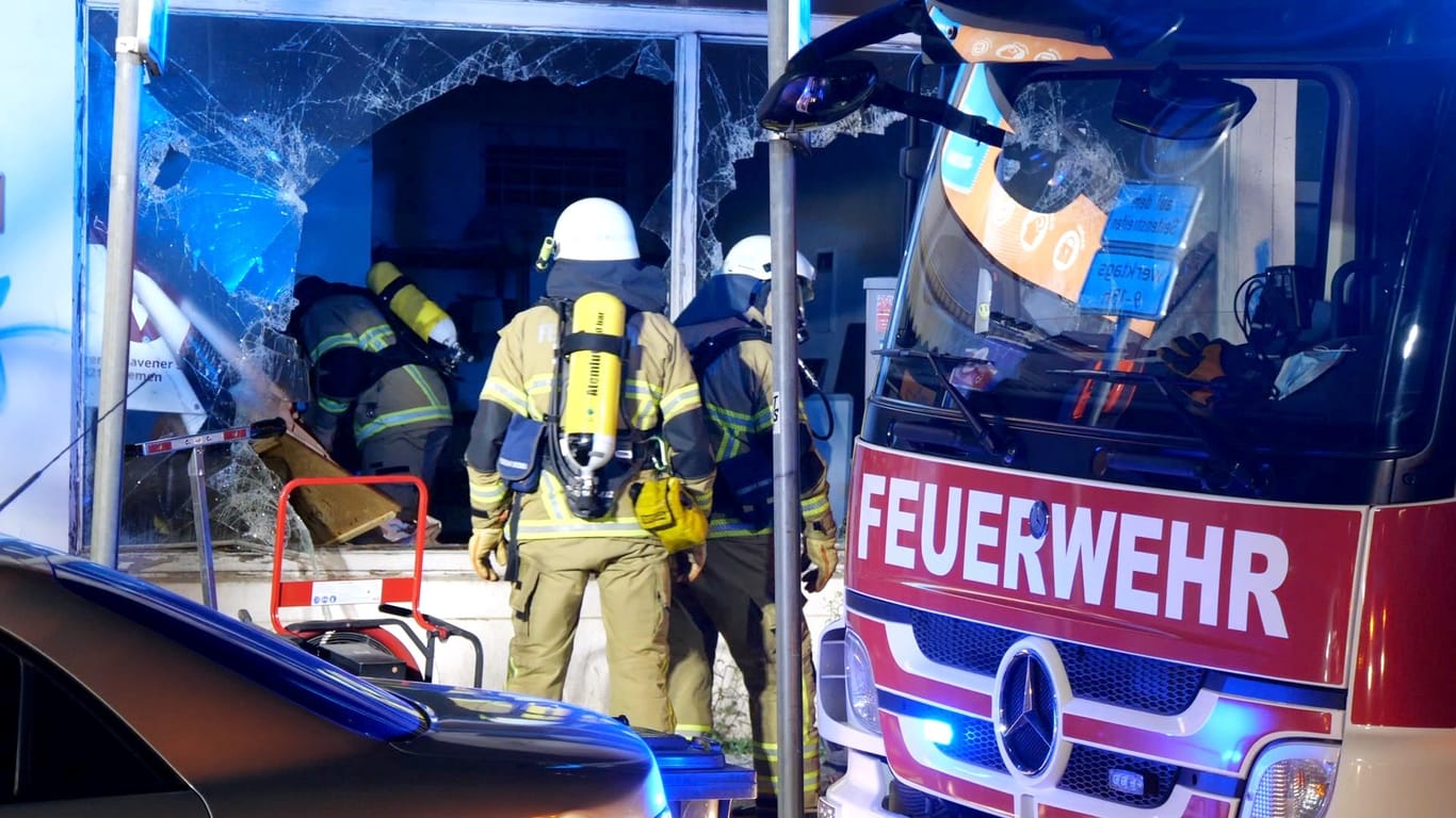 Einsatzkräfte der Feuerwehr steigen durch ein zerbrochenes Fenster in ein Ladenlokal: Der Brand konnte schnell gelöscht werden.