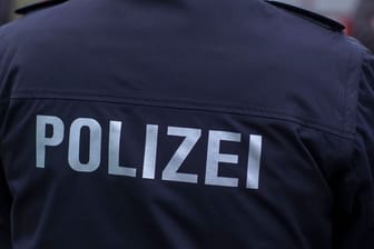 "Polizei" steht auf der Uniform eines Polizisten (Symbolbild): Der Tatverdächtige hat die Waffen illegal besessen.