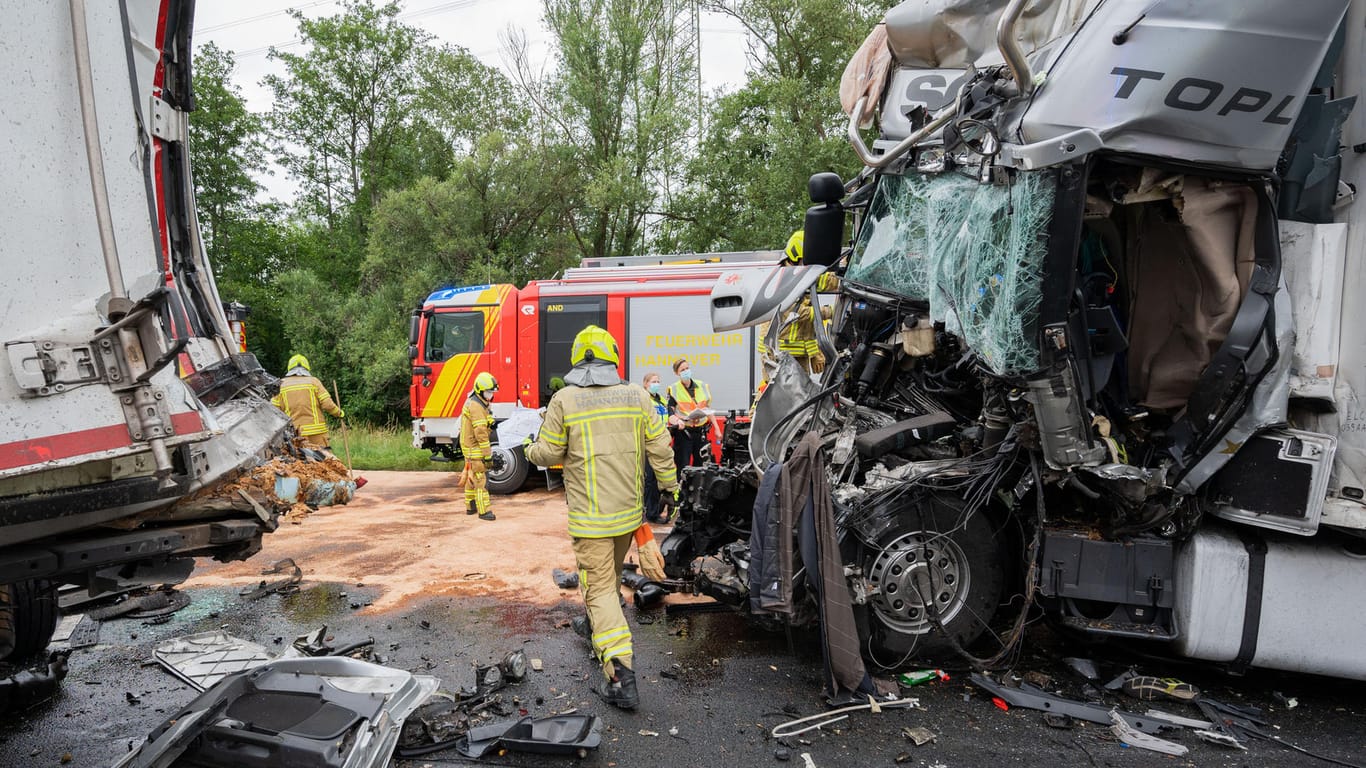 Einsatzkräfte der Feuerwehr stehen an einem LKW-Wrack auf der Autobahn A2 am Autobahnkreuz Hannover-Buchholz. Bei einem Unfall mit drei beteiligten LKW ist am Morgen ein LKW-Fahrer ums Leben gekommen.