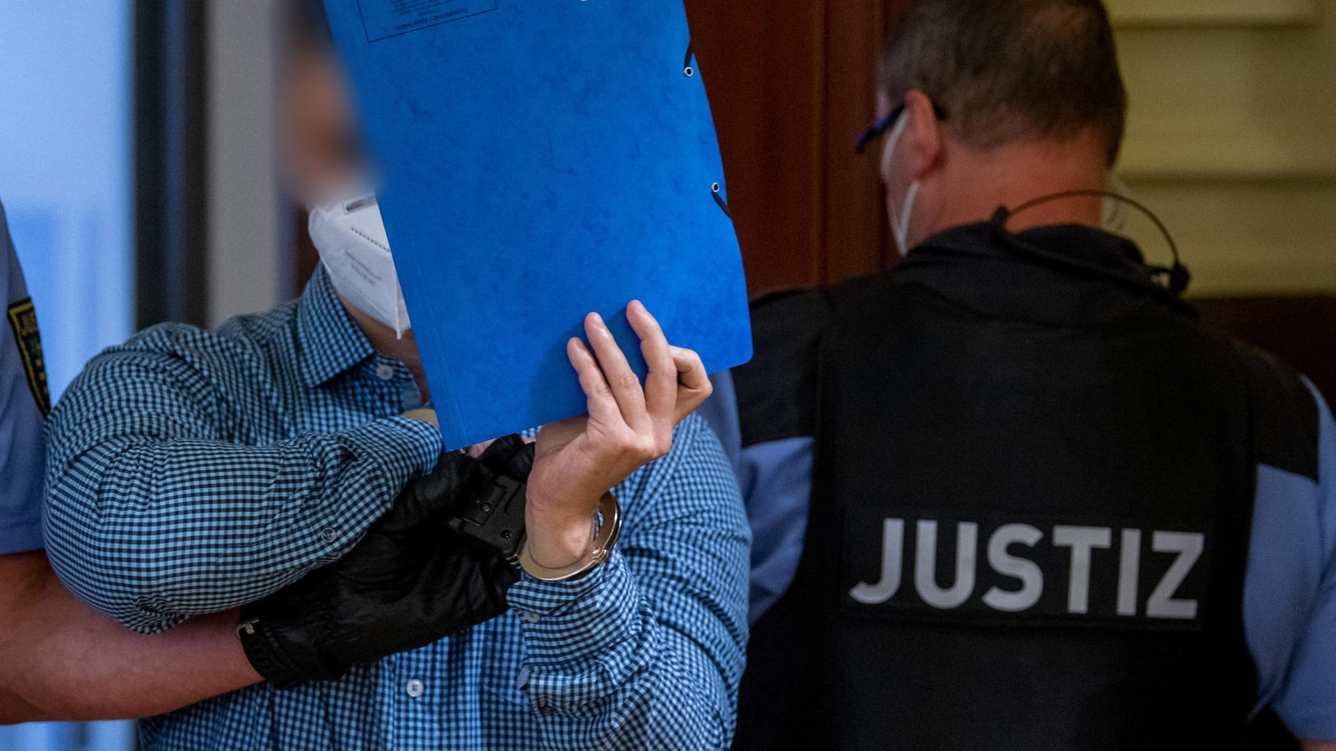 Ein Mann wird von Justizpersonal in den Verhandlungssaal geführt: Die Staatsanwaltschaft wirft dem Angeklagten Mord vor. Ein Mann wird von Justizpersonal in den Verhandlungssaal geführt: Die Staatsanwaltschaft wirft dem Angeklagten Mord vor.