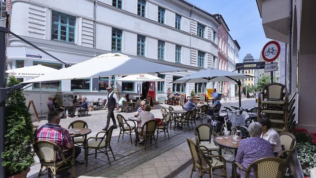 Passanten genießen in einem Straßencafé das sommerliche Wetter