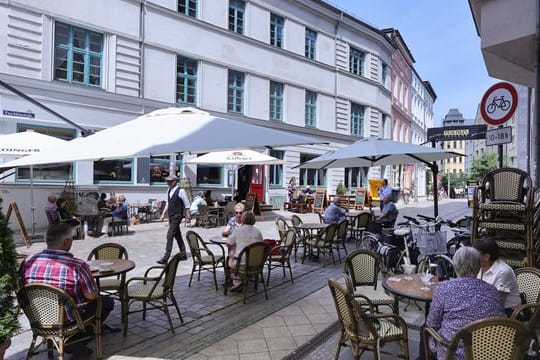 Passanten genießen in einem Straßencafé das sommerliche Wetter