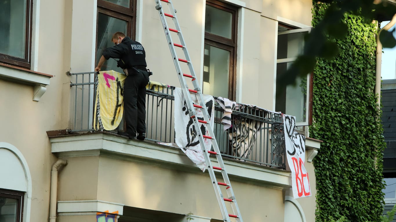 Ein Polizist nimmt Banner von einem Balkon ab: In dem Haus fanden die Beamten Matratzen und Verpflegung.