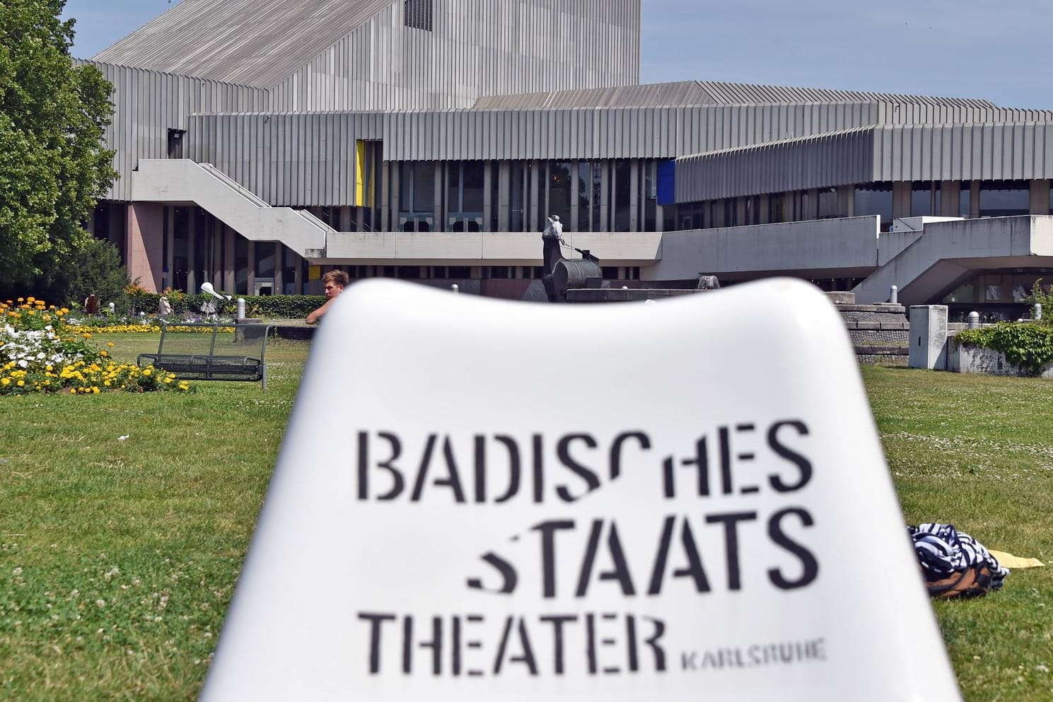 Das Badische Staatstheater spiegelt sich in einer Wasserfläche (Archivbild): Das Haus wird für viel Geld saniert.