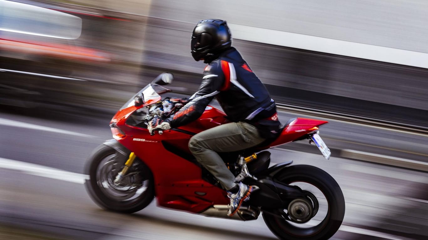 Ein Motorradfahrer fährt schnell durch die Stadt (Symbolbild): Bei seiner Flucht missachtete der Raser mehrere rote Ampeln.