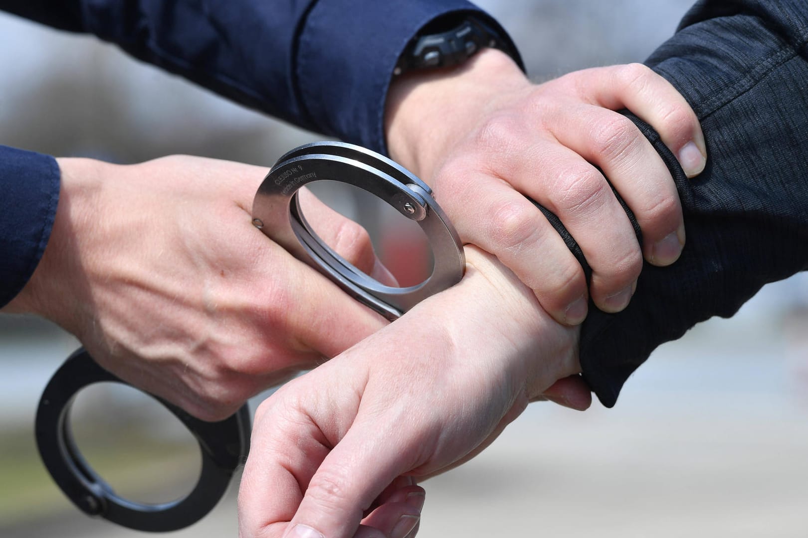 Ein Polizist legt einer Person Handschellen an (Symbolbild): Die beiden Randalierer wurden in Polizeigewahrsam genommen.