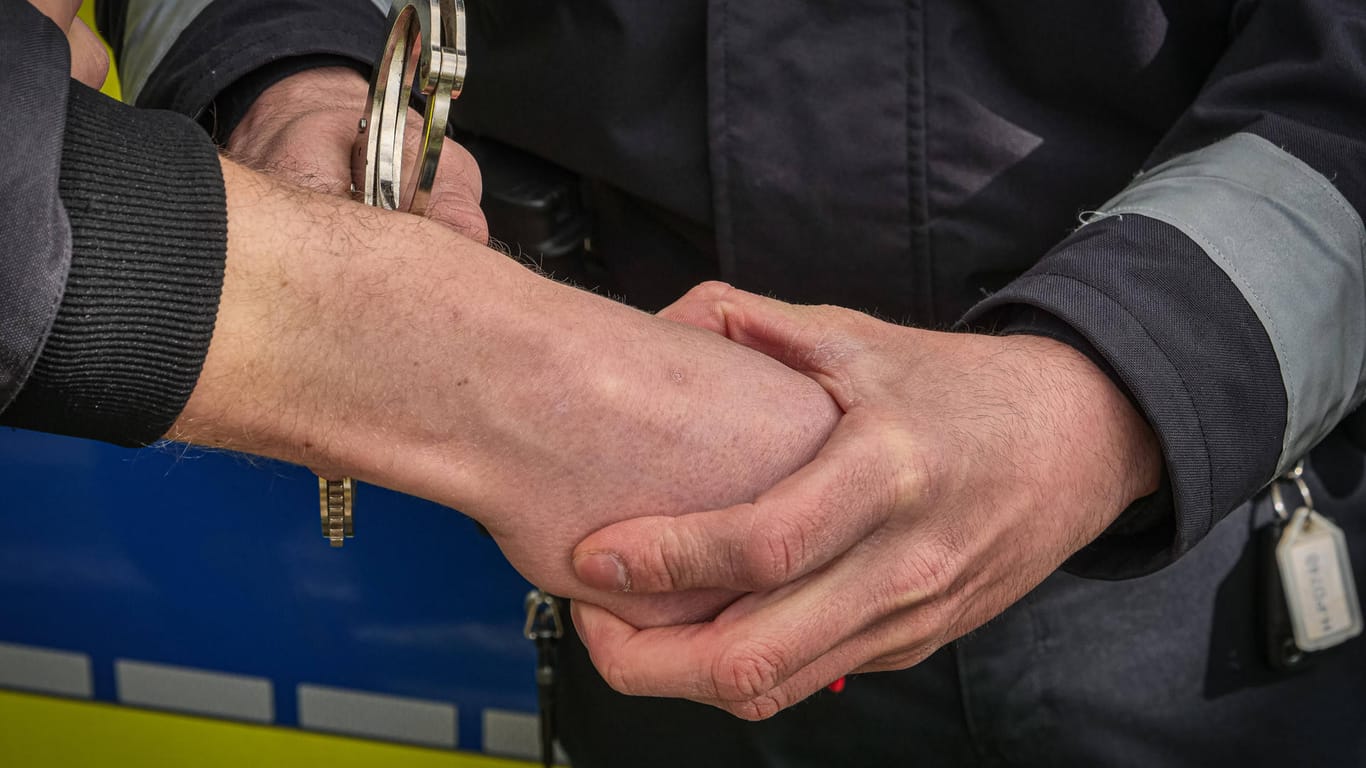 Ein Polizist legt einem Mann Handschellen an (Symbolbild): Nachdem er mutmaßlich sich und seine Kinder verbrennen wollte, ist ein Mann in Untersuchungshaft untergebracht worden.