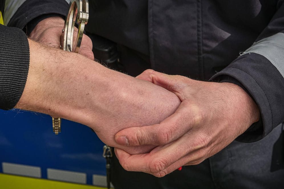 Ein Polizist legt einem Mann Handschellen an (Symbolbild): Nachdem er mutmaßlich sich und seine Kinder verbrennen wollte, ist ein Mann in Untersuchungshaft untergebracht worden.