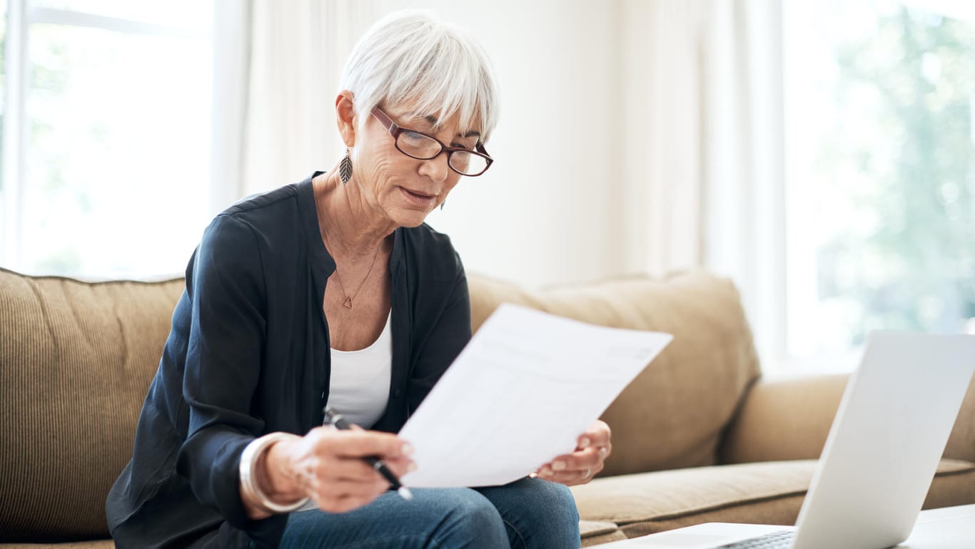 Eine ältere Frau sortiert ihre Finanzen (Symbolbild): Viele Menschen gleichen Abschläge der Rente aus.