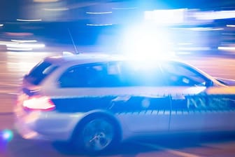 Ein Polizeiauto fährt mit Blaulicht über eine Straße