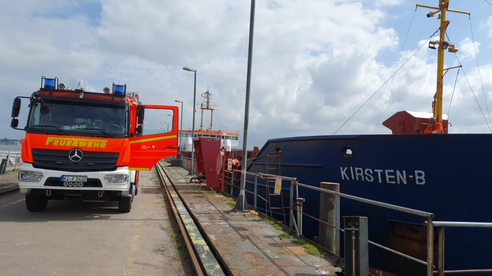 Ein Einsatzfahrzeug der Feuerwehr steht im Hafen neben dem Schüttgutfrachter. Für die Löscharbeiten musste das Schiff zunächst in einen anderen Hafen verlegt werden. Ein Einsatzfahrzeug der Feuerwehr steht im Hafen neben dem Schüttgutfrachter. Für die Löscharbeiten musste das Schiff zunächst in einen anderen Hafen verlegt werden.