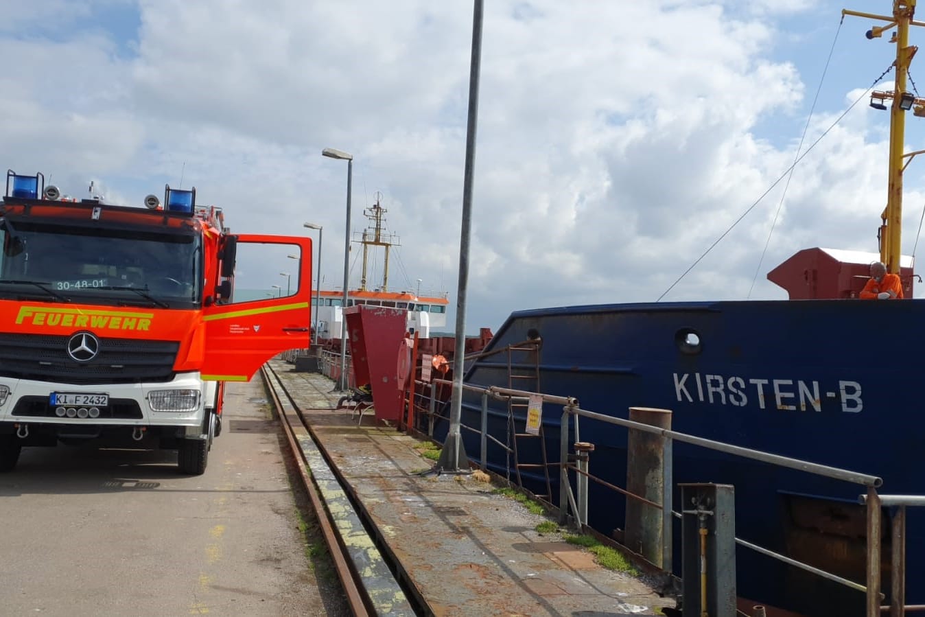 Ein Einsatzfahrzeug der Feuerwehr steht im Hafen neben dem Schüttgutfrachter. Für die Löscharbeiten musste das Schiff zunächst in einen anderen Hafen verlegt werden.