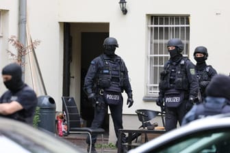 Polizisten stehen neben einer geöffneten Tür: Mehrere Beamte haben Wohn- und Geschäftsräume in Leipzig durchsucht.
