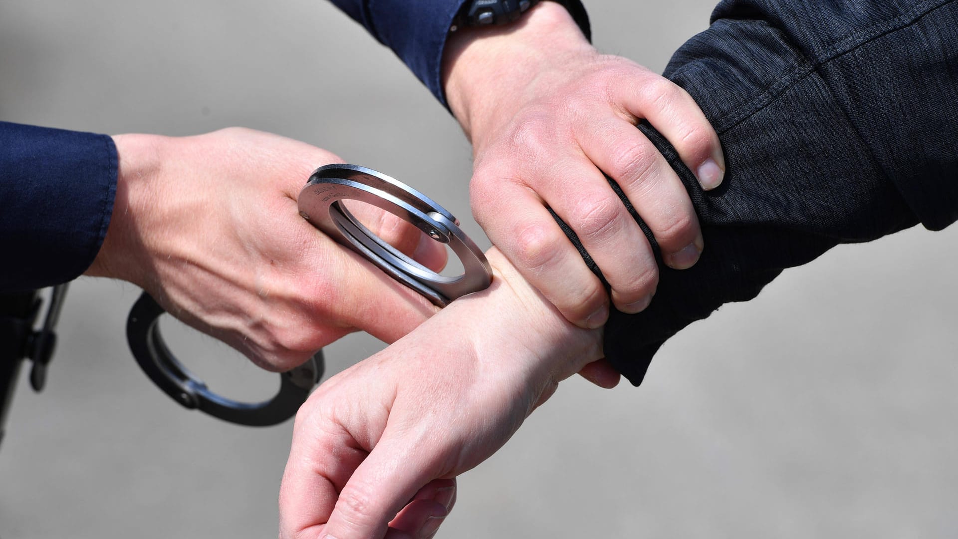 Ein Polizist legt einem Verdächtigen Handschellen an (Symbolbild): Auf dem Gelände wurde unter anderem ein aufgebrochenes Auto entdeckt.