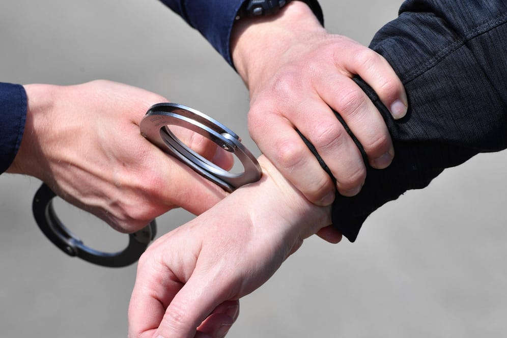 Ein Polizist legt einem Mann Handschellen an (Symbolbild): Nach Zeugenhinweisen konnte die Polizei einen Verdächtigen fassen.