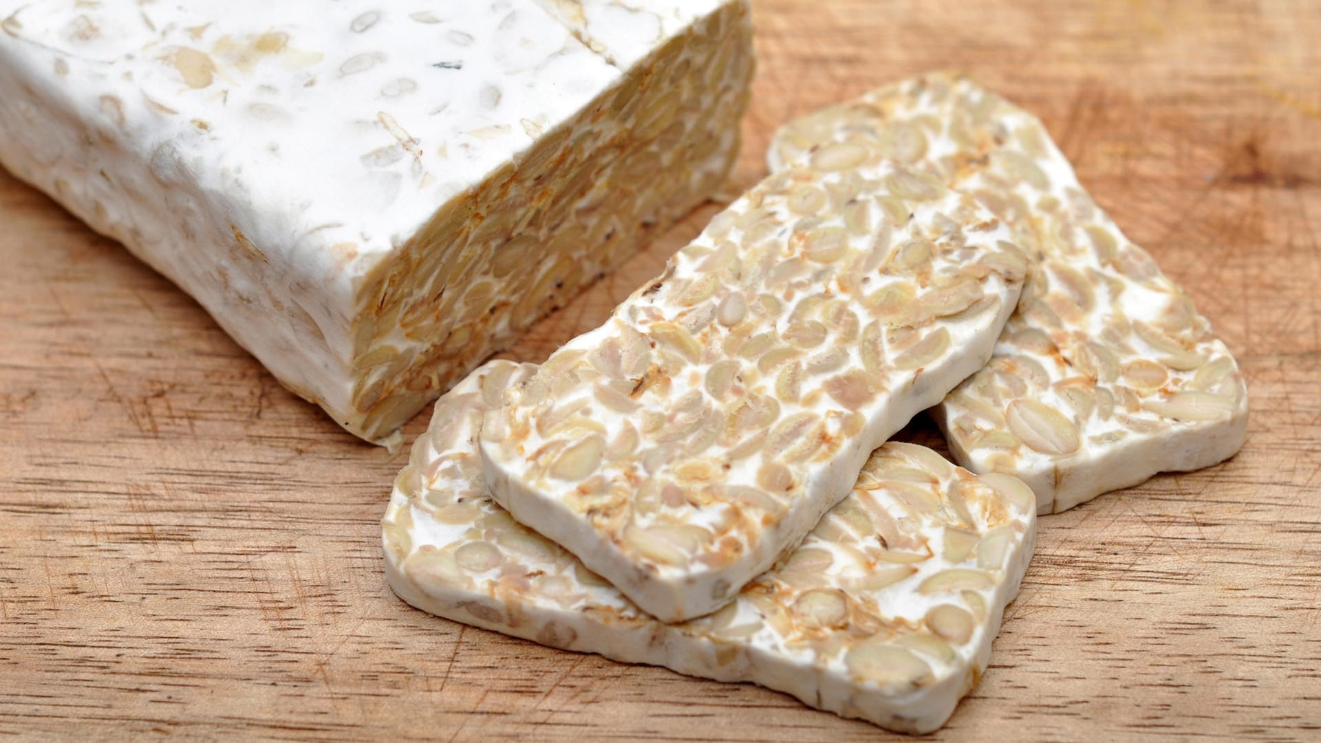 Tempeh: Für Tempeh werden ganze Sojabohnen verarbeitet, die mit Schimmelpilzen fermentiert werden.