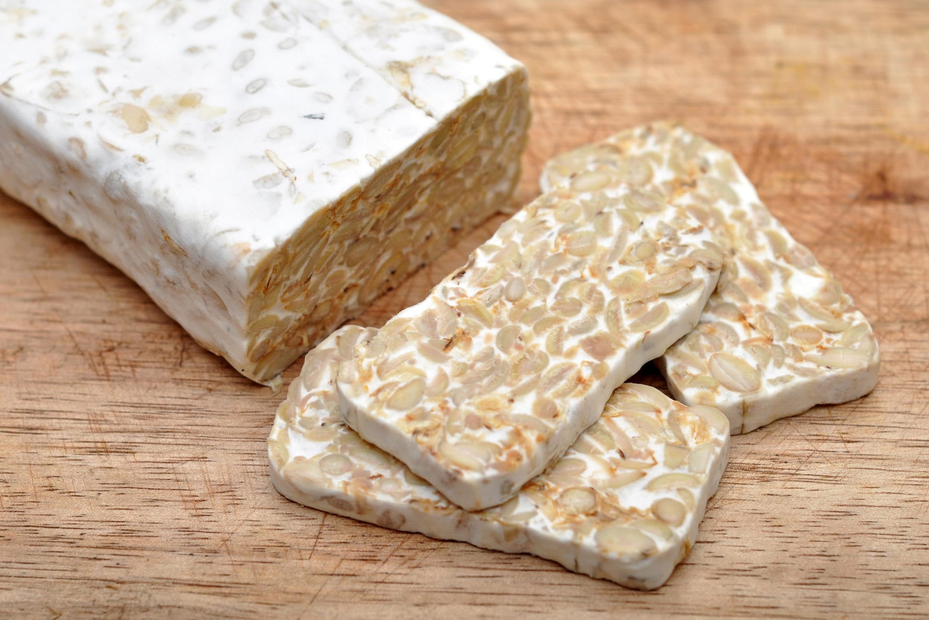 Tempeh: Für Tempeh werden ganze Sojabohnen verarbeitet, die mit Schimmelpilzen fermentiert werden.