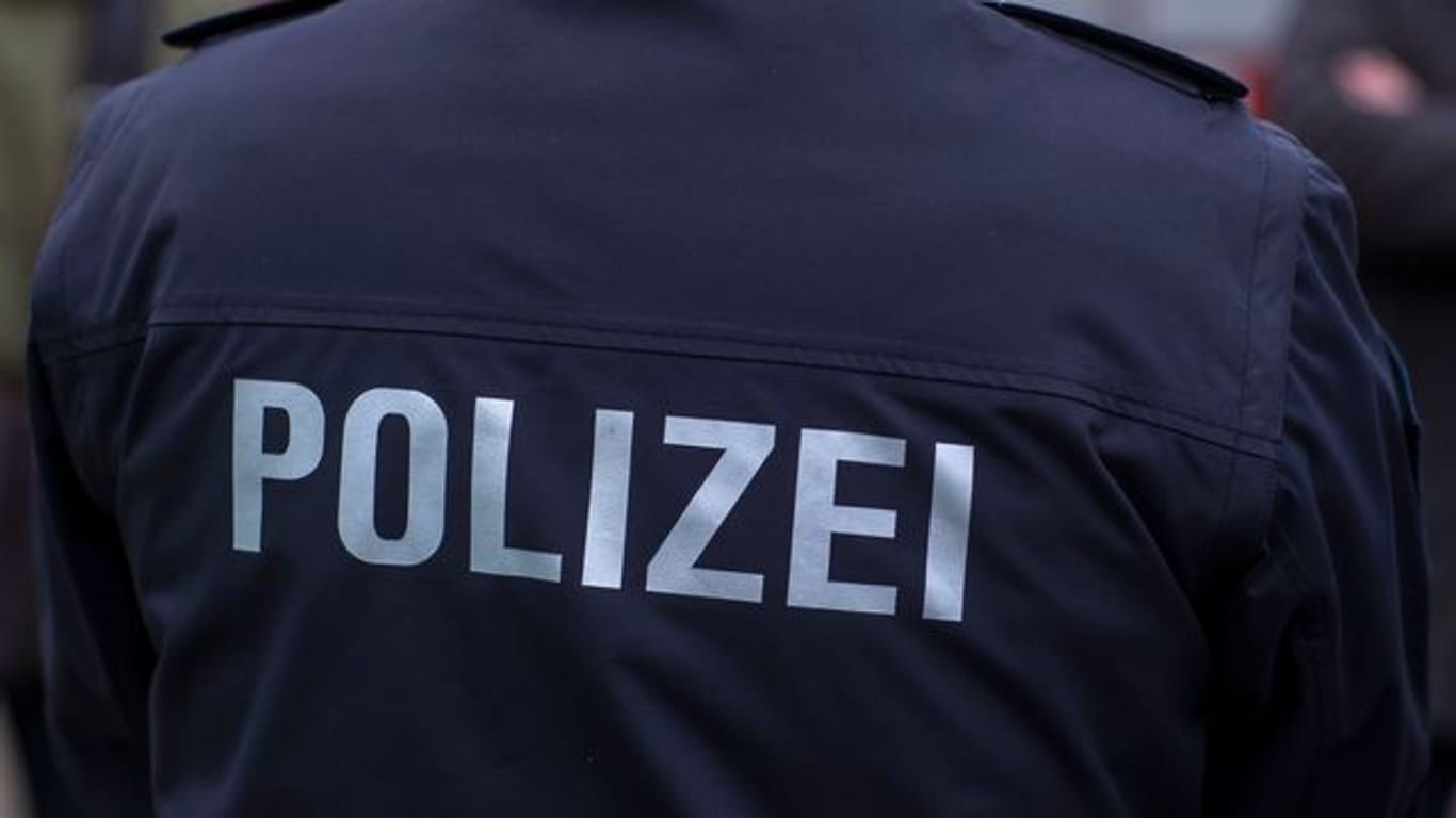 "Polizei" steht auf der Uniform eines Polizisten (Symbolbild): Die Mutter tauchte bei dem 23-Jährigen auf und wollte mit ihm reden, dann eskalierte es.