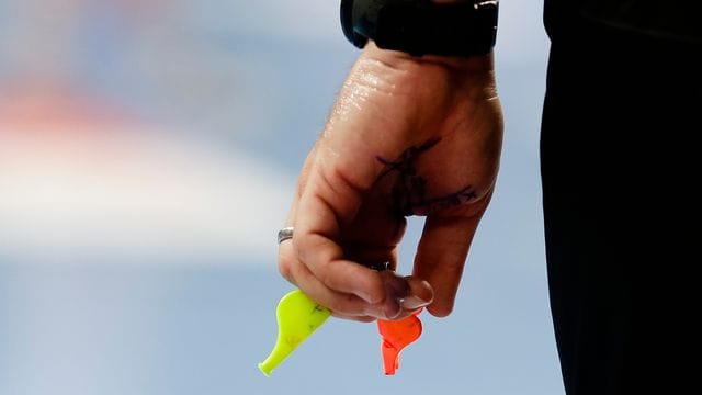 Ein Schiedsrichter hält zwei Pfeiffen in der Hand