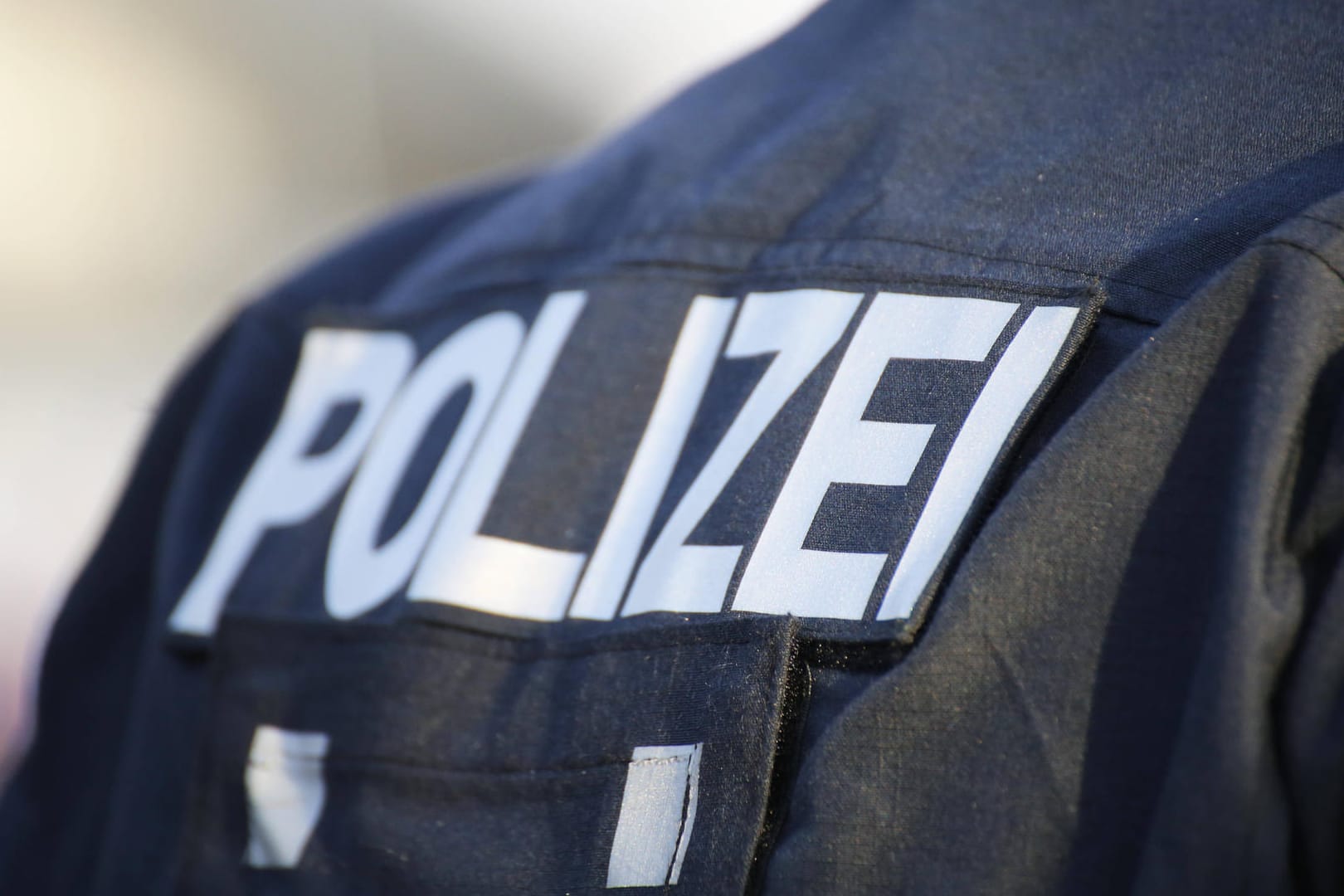 "Polizei" steht auf der Jacke eines Beamten (Symbolbild): Die Polizisten stellten eine Vielzahl von Artikeln sicher.