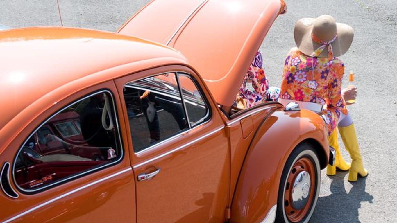 Eine Frau sitzt an ihrem VW-Käfer bei einem Treffen von Käfer-Besitzern (Archivbild): "Dass so viele Fans unserer Einladung an die Geburtsstätte des Käfers folgen, macht uns sehr stolz."