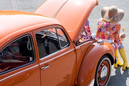 Eine Frau sitzt an ihrem VW-Käfer bei einem Treffen von Käfer-Besitzern (Archivbild): "Dass so viele Fans unserer Einladung an die Geburtsstätte des Käfers folgen, macht uns sehr stolz."