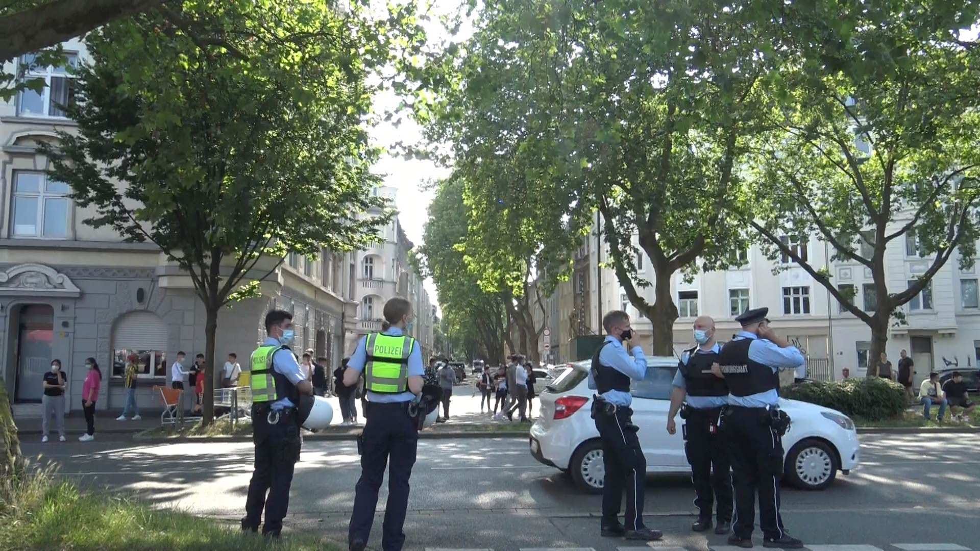 Die Polizei im Einsatz an der Straße: Auf dem Supermarktparkplatz hatten sich mehr als 1.000 Menschen versammelt.