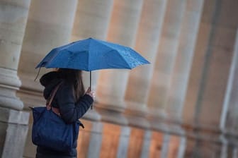 Eine Passantin geht bei Regen durch die Stadt