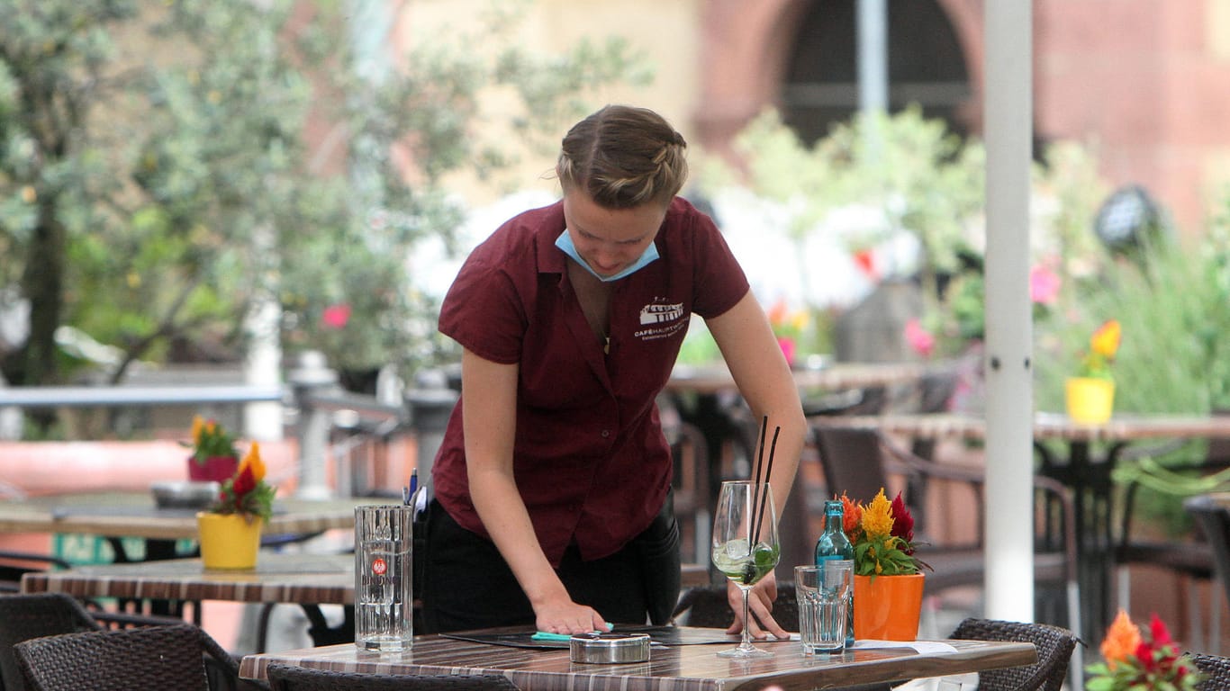 Eine Kellnerin wischt einen Tisch ab (Symbolbild): In Baden-Württemberg treten weitere Corona-Lockerungen in Kraft.