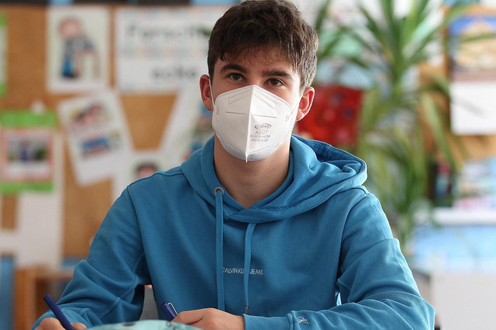 Ein Schüler sitzt mit Maske im Unterricht (Symbolbild): Kinder und Jugendliche werden derzeit nicht flächendeckend geimpft, für sie gelten noch zahlreiche Einschränkungen.