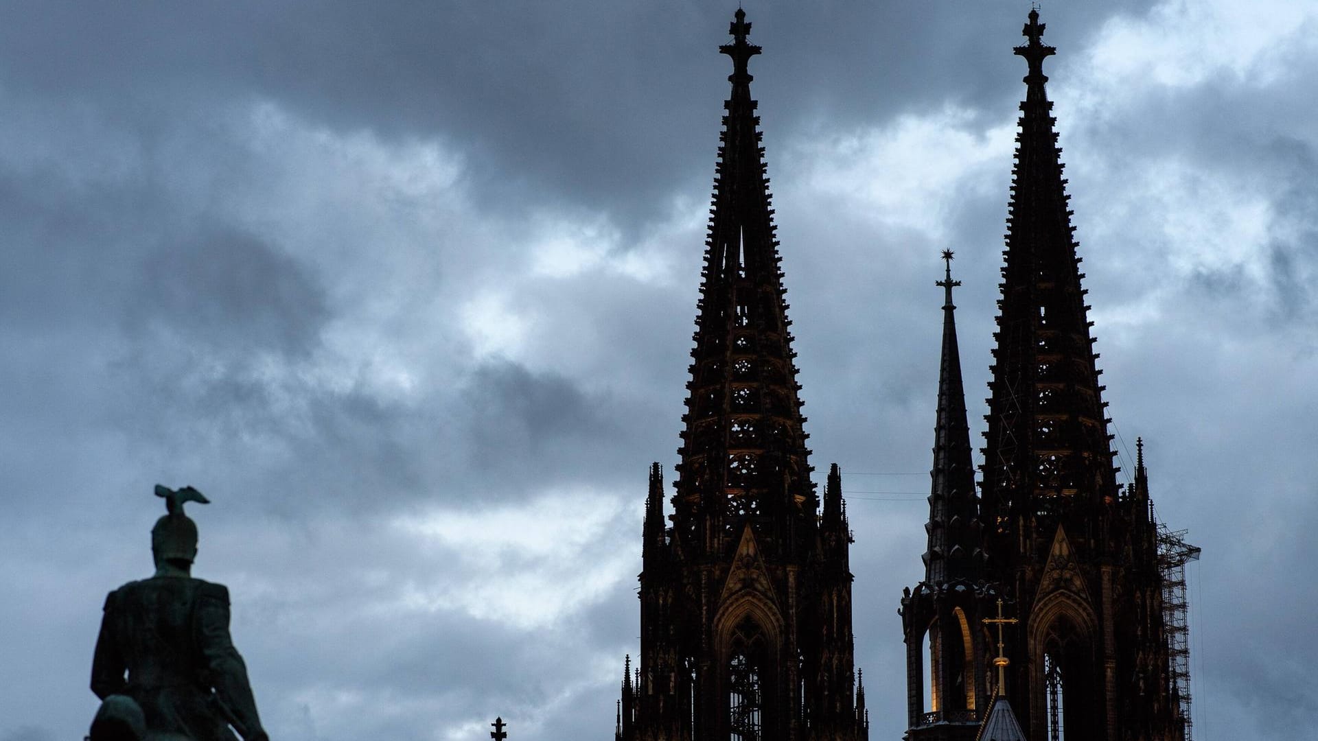 Graue Wolken hinter dem Kölner Dom (Archvbild): Die neue Woche startet in Köln zwar warm, aber mit Gewittern.