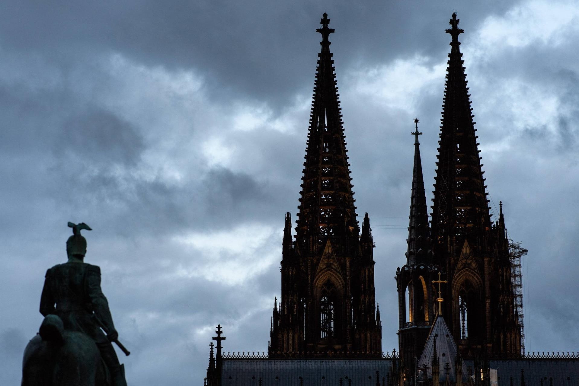 Graue Wolken hinter dem Kölner Dom (Archvbild): Die neue Woche startet in Köln zwar warm, aber mit Gewittern.