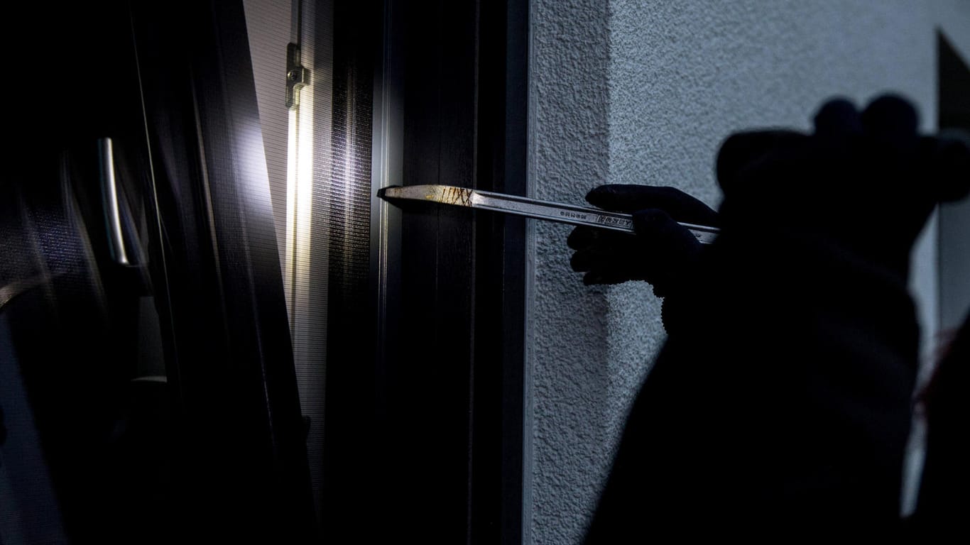 Ein Einbrecher versucht mit einem Brecheisen, ein Fenster aufzubrechen (Symbolbild): In Bornheim bei Bonn ist der Bewohner einer Wohnung von einem Einbrecher überrascht worden.