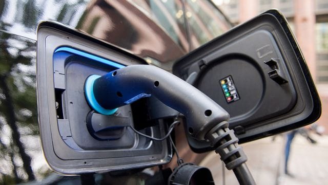 Ein Stecker steckt an einer Ladestation für Elektrofahrzeuge in einem Auto. Ein Stecker steckt an einer Ladestation für Elektrofahrzeuge in einem Auto.