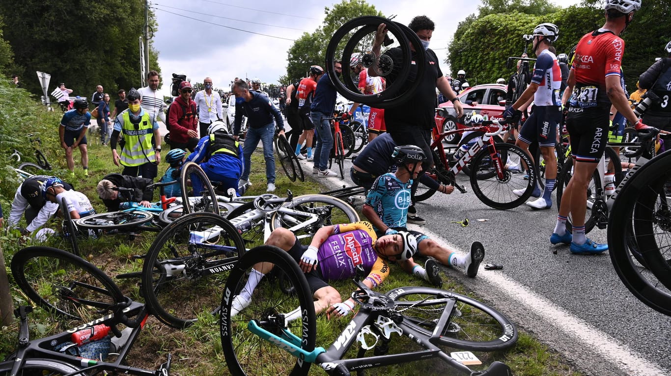Fahrer der Tour de France liegen am Boden: Die führ den Massensturz verantwortliche Zuschauerin wird offenbar polizeilich gesucht.