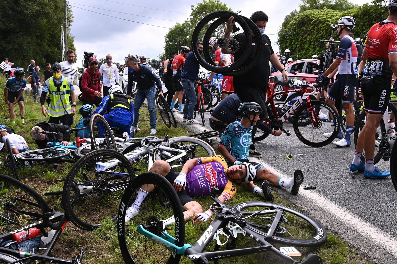 Fahrer der Tour de France liegen am Boden: Die führ den Massensturz verantwortliche Zuschauerin wird offenbar polizeilich gesucht.