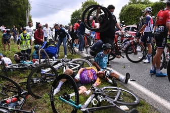 Fahrer der Tour de France liegen am Boden: Die führ den Massensturz verantwortliche Zuschauerin wird offenbar polizeilich gesucht.