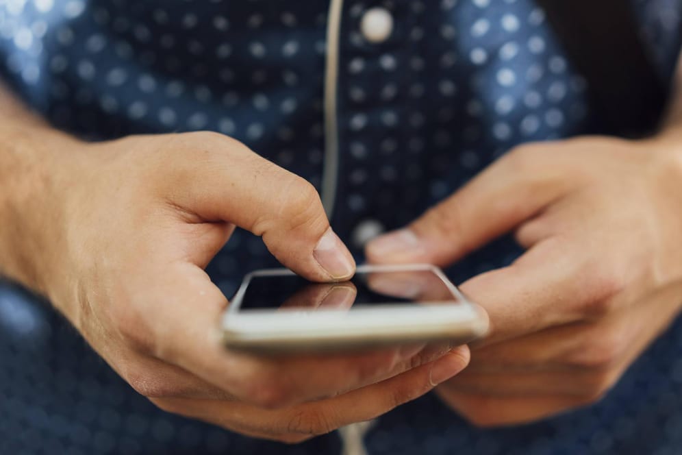 Ein Mann mit Smartphone (Symbolbild): Verbraucherschützer warnen vor gefährlichen SMS.