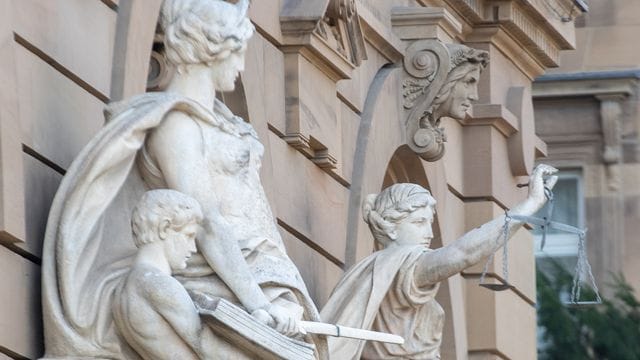 Vor einem Gerichtsgebäude steht u.a. eine Statue der Justitia