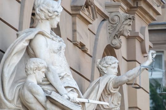 Vor einem Gerichtsgebäude steht u.a. eine Statue der Justitia