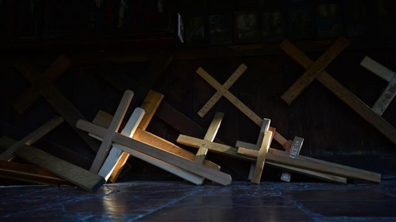Holzkreuze liegen auf dem Boden (Symbolbild):Missbrauchsopfer der Erzdiözese München haben Entschädigungszahlungen bekommen.
