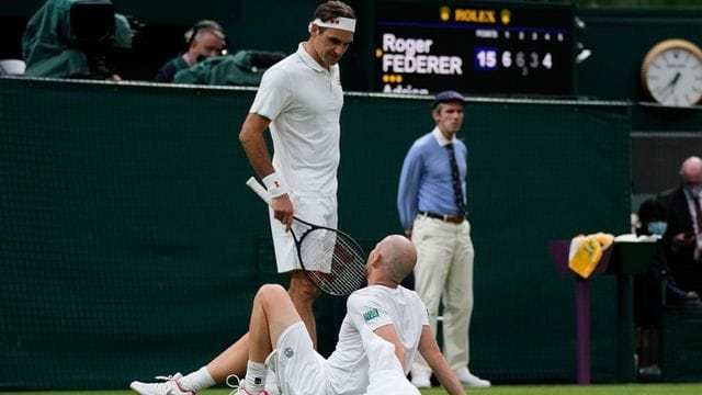 Roger Federer spricht mit Adrian Mannarino, der verletzt am Boden liegt. Roger Federer spricht mit Adrian Mannarino, der verletzt am Boden liegt.