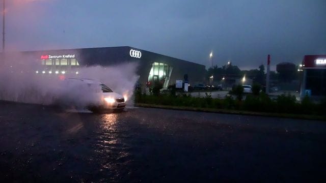 Ein Auto fährt durch eine überflutete Straße: In NRW hat es heftige Regenfälle gegeben. Ein Auto fährt durch eine überflutete Straße: In NRW hat es heftige Regenfälle gegeben.